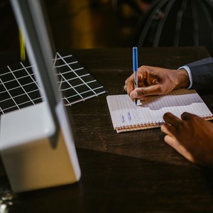 Muž zapisuje poznámky při online výuce angličtiny, symbol individuálního přístupu a efektivního učení s jazykovou školou TOPLINGVA.
