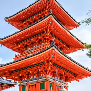 Tradiční japonská pagoda s výraznými oranžovými a červenými dřevěnými prvky a tmavými střechami.