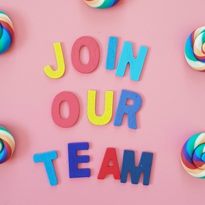 Barevné dřevěné písmenka uprostřed růžového pozadí tvoří nápis 