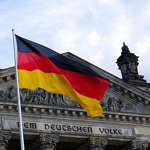 Německá vlajka zavěšená před historickou budovou v Německu, symbolizující německou kulturu a jazyk.