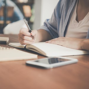 Studentka si zapisuje poznámky během jazykového kurzu, symbol motivace a radosti z učení cizího jazyka v jazykové škole TOPLINGVA.