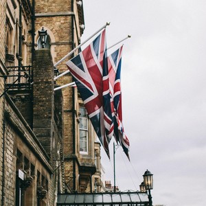 Dvě britské vlajky vlají na stožárech na fasádě budovy.