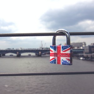 Visací zámek s britskou vlajkou, zavěšený na mostě nad řekou.