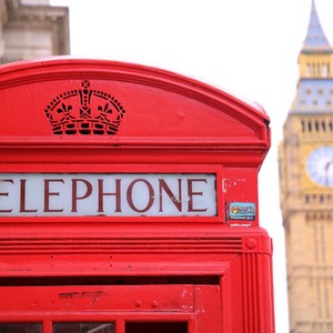 Ikonická červená londýnská telefonní budka s nápisem stojící před budouvou Big Ben.