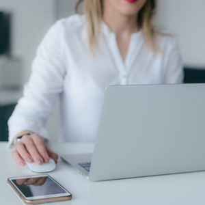 Žena studující online kurz angličtiny v TOPLINGVĚ, sedí u stolu s notebookem a telefonem.  