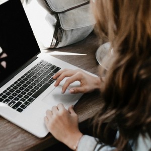 Žena pracuje na notebooku, zapisuje poznámky a připravuje se na studium překladatelství a tlumočnictví.