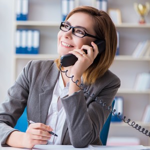 Žena hovoří po telefonu a zlepšuje si angličtinu prostřednictvím telefonických lekcí.